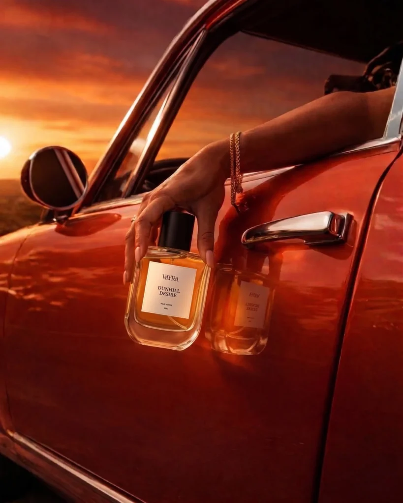 A hand holding Vayra Dunhill Desire bottle out of a red vintage car window; best fragrance in Pakistan.