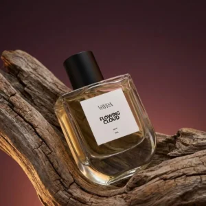Vayra Flowing Cloud perfume bottle leaning against weathered driftwood; best fragrance in Pakistan with golden liquid visible